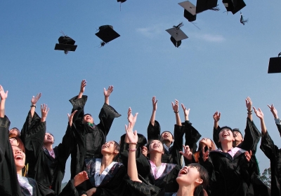 studenten die hun afstudeer hoofddeksel in de lucht gooien